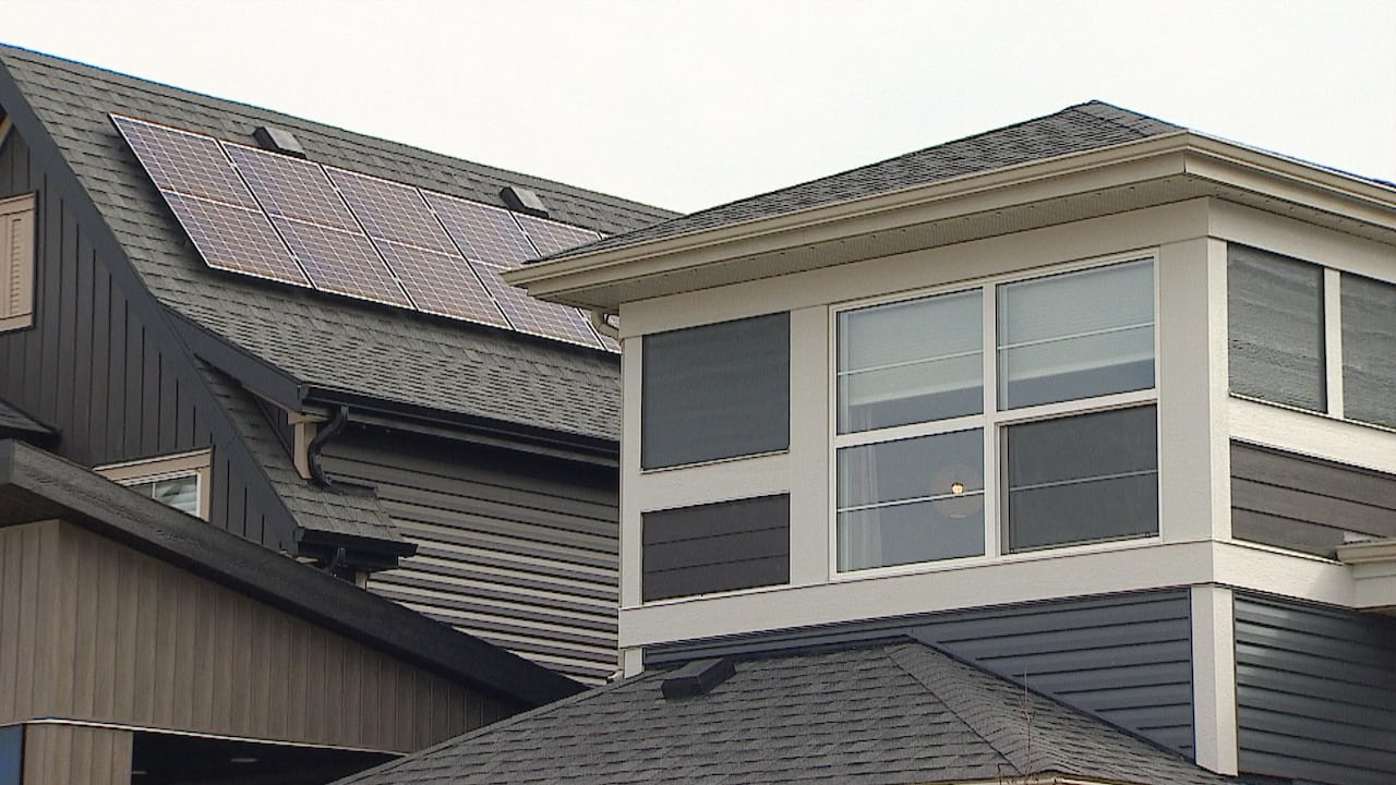 default-467 Low angle shot of modern house with turret. Roof behind has at least six solar panels attached to it.