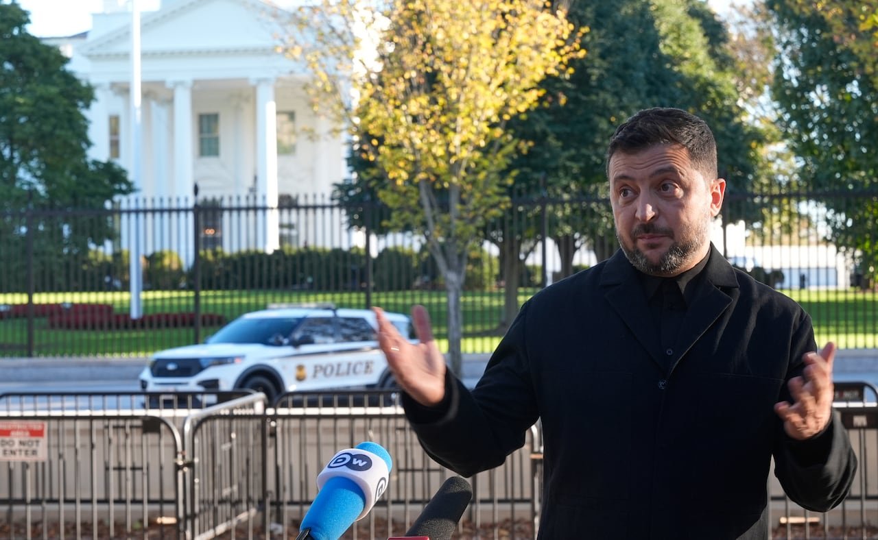 default-525 Zelenskyy gestures with both hands, with the White House and a police vehicle visible in the background.