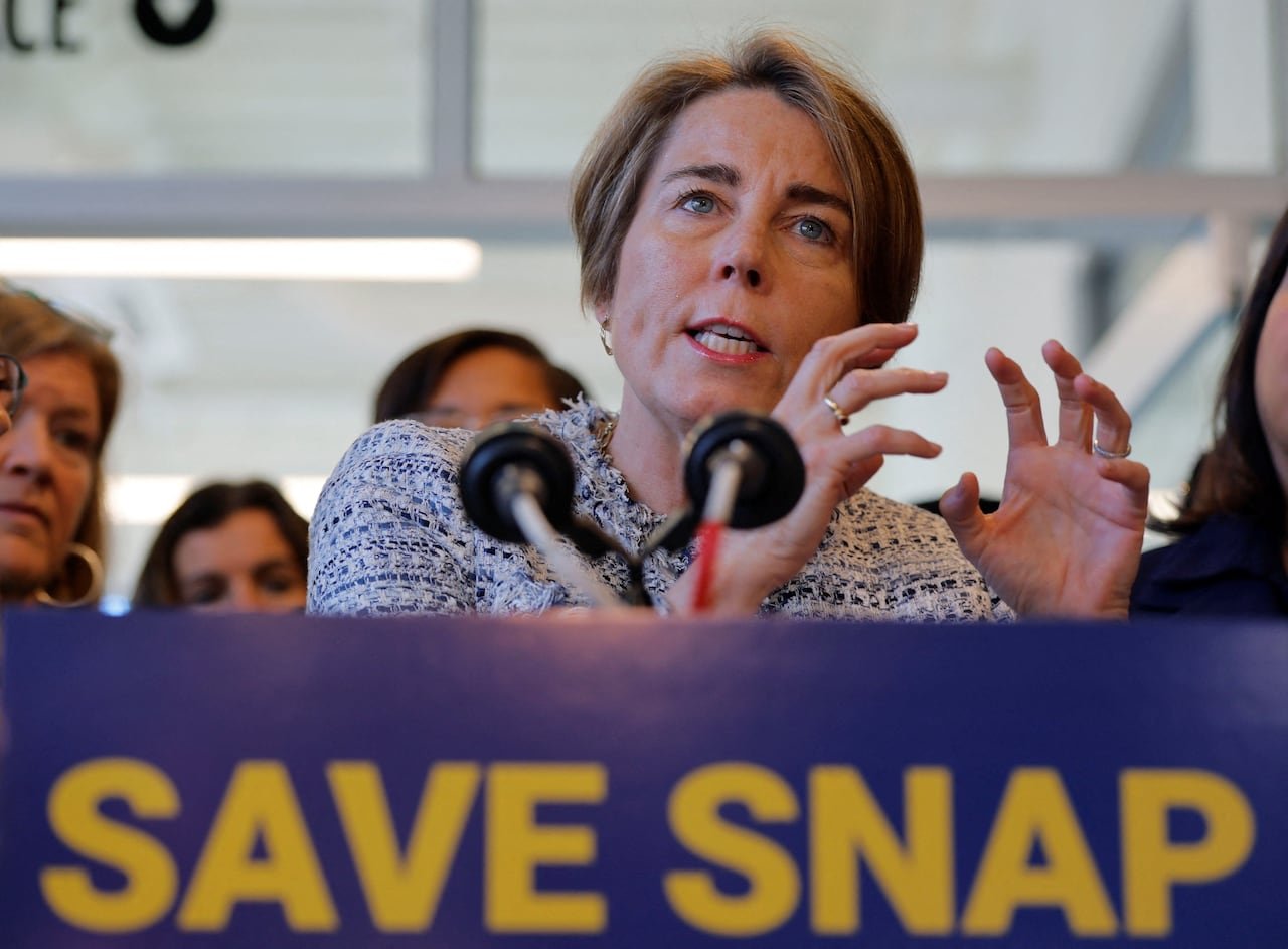 default-141 A woman with hair that goes to her ears gestures in a closeup shot while speaking at a podium that has a placard on front that says, "Save Snap."