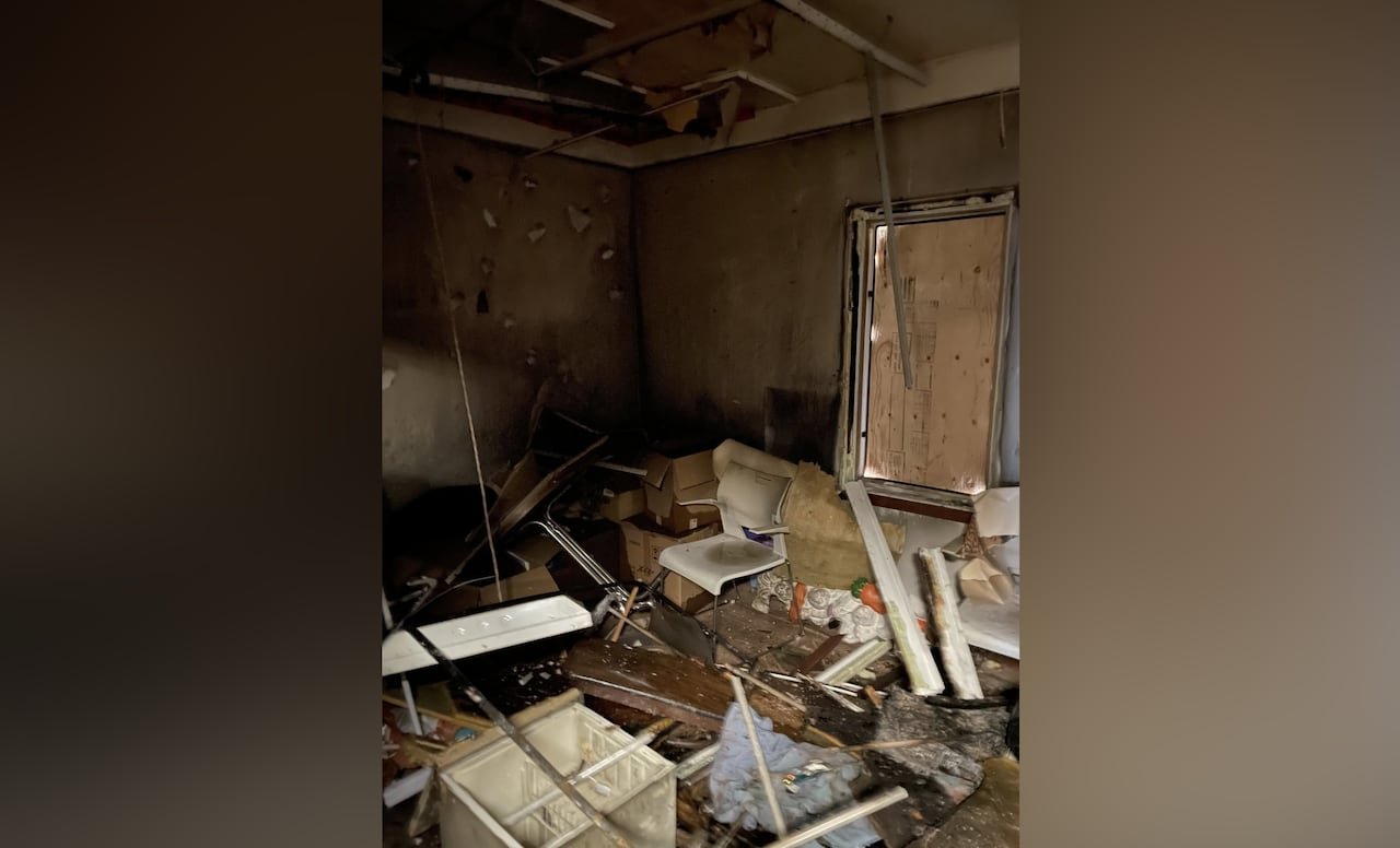 Furniture and other items are scattered across the floor in an office building, with a boarded-up window.